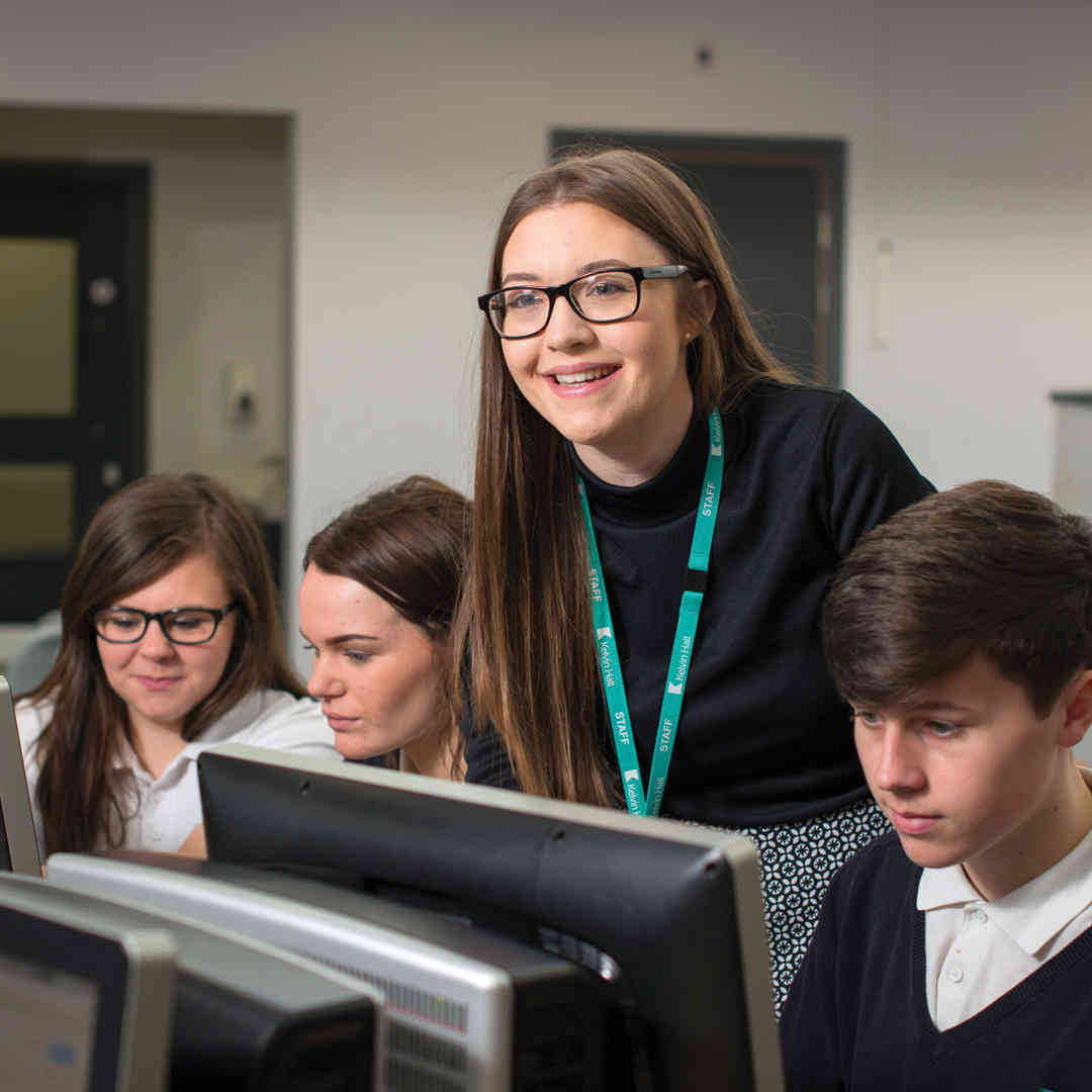 A student teacher with a group of students working in a computer room