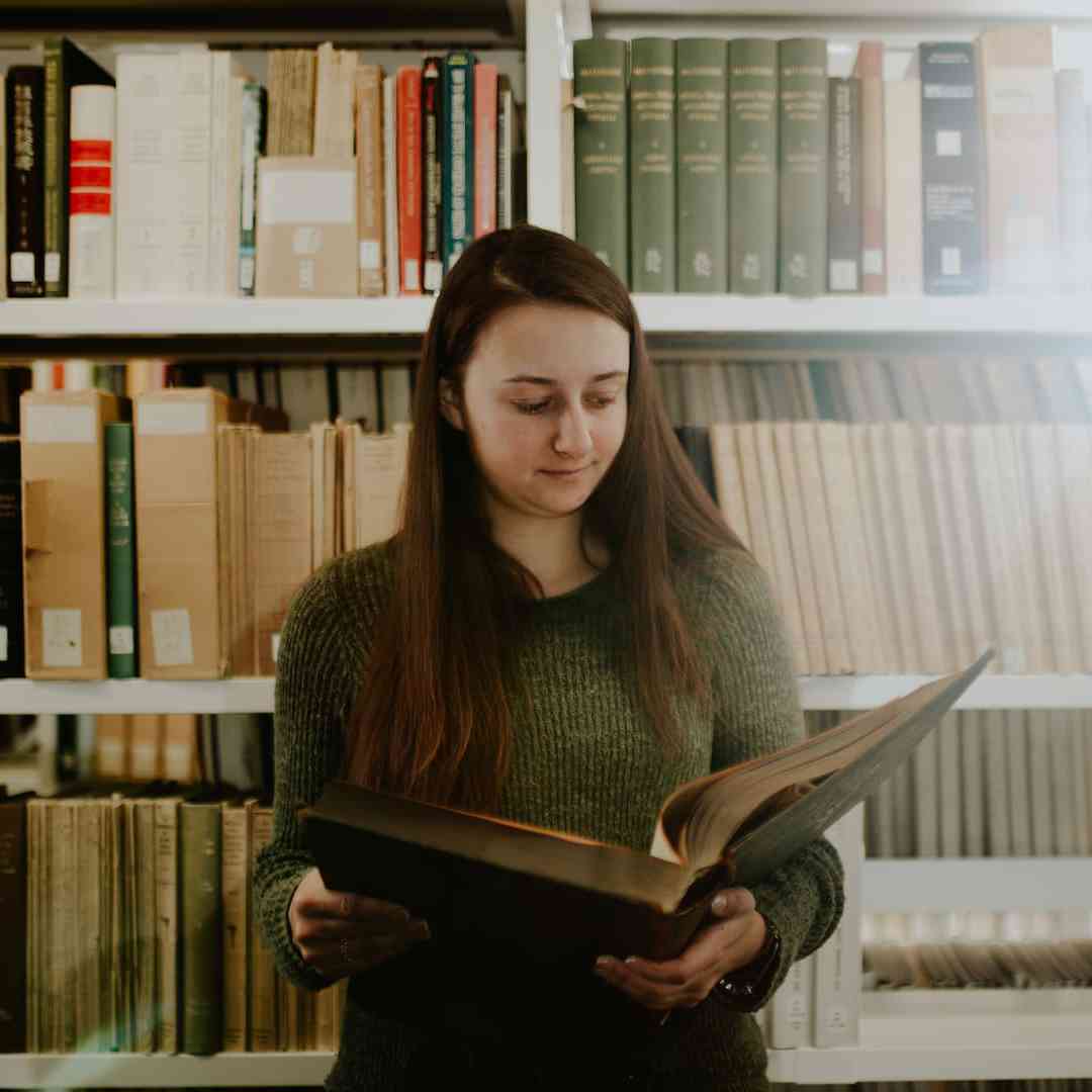 A history student reading a large book in the library
