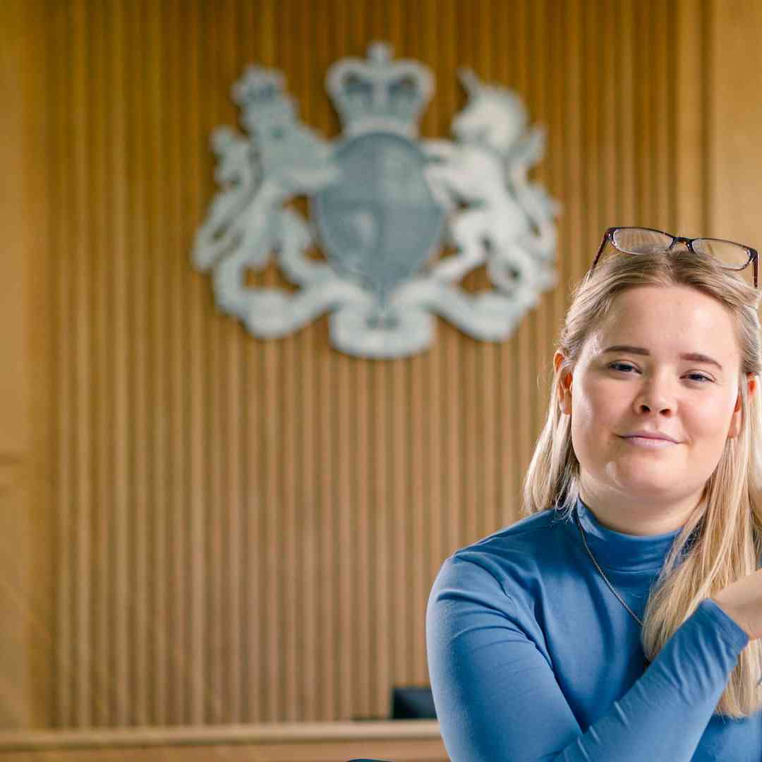 A law student poses in a wood-panelled courtroom