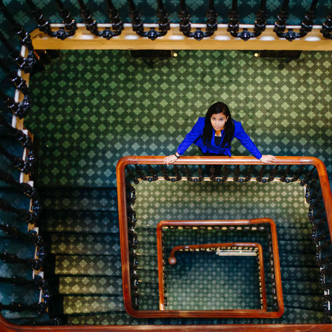 Hull Politics student, Jacqueline Gomes-Neves, stands on a winding staircase in Westminster looking up to the camera.