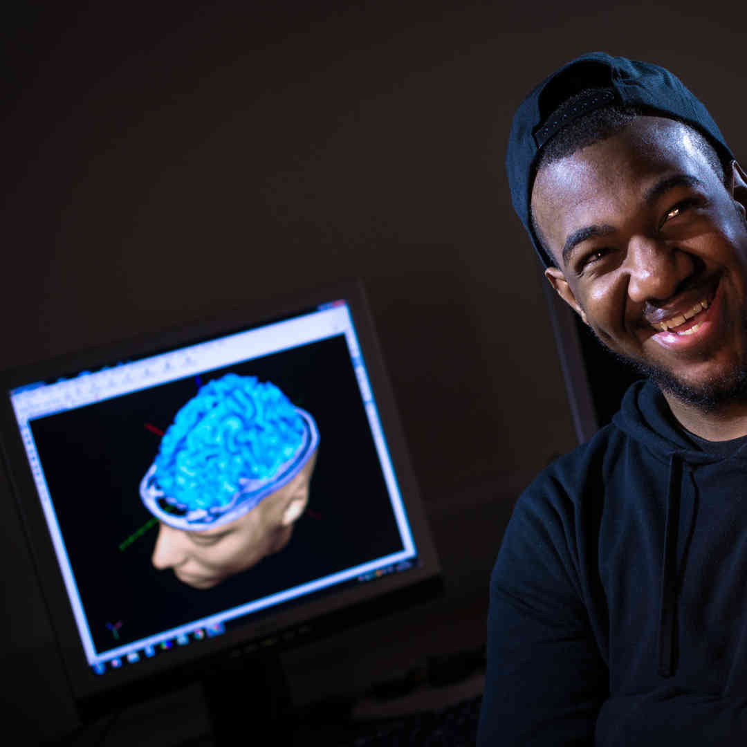 aaron hall, psychology student in front of a brain on a screen