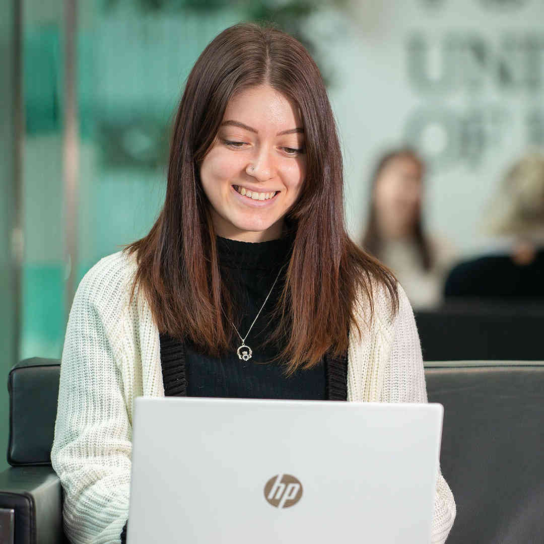 A law student works on a laptop in the Business School foyer