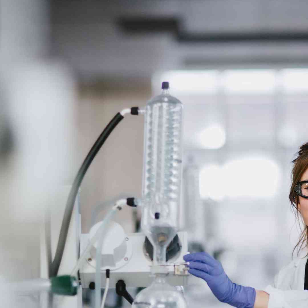 A female student in a white lab coat working on equipment in a chemistry lab