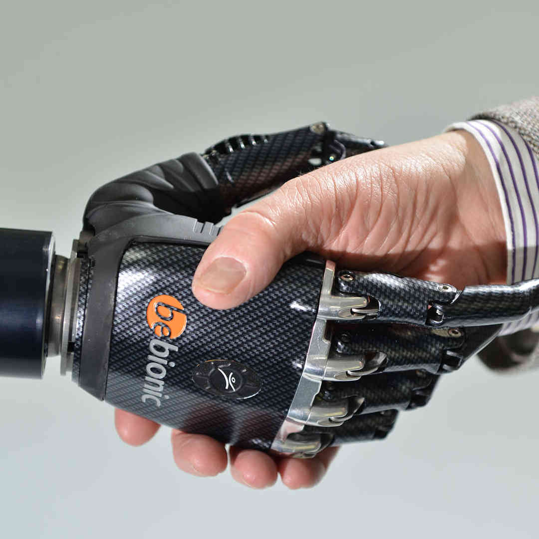 A human hand shaking a robotic hand in greeting.