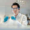 A chemistry student wearing protective equipment stands in a lab
