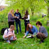 Six students crouch on grass while taking samples during Environmental Science Field Work