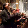 A choir holding hymn sheets and singing in a church.