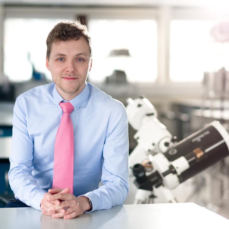 Astrophysics student in a laboratory in front of a large telescope