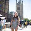Hull Politics student, Lucy Dunwell, stands smiling outside the Houses of Parliament while a crowd of people walk by.