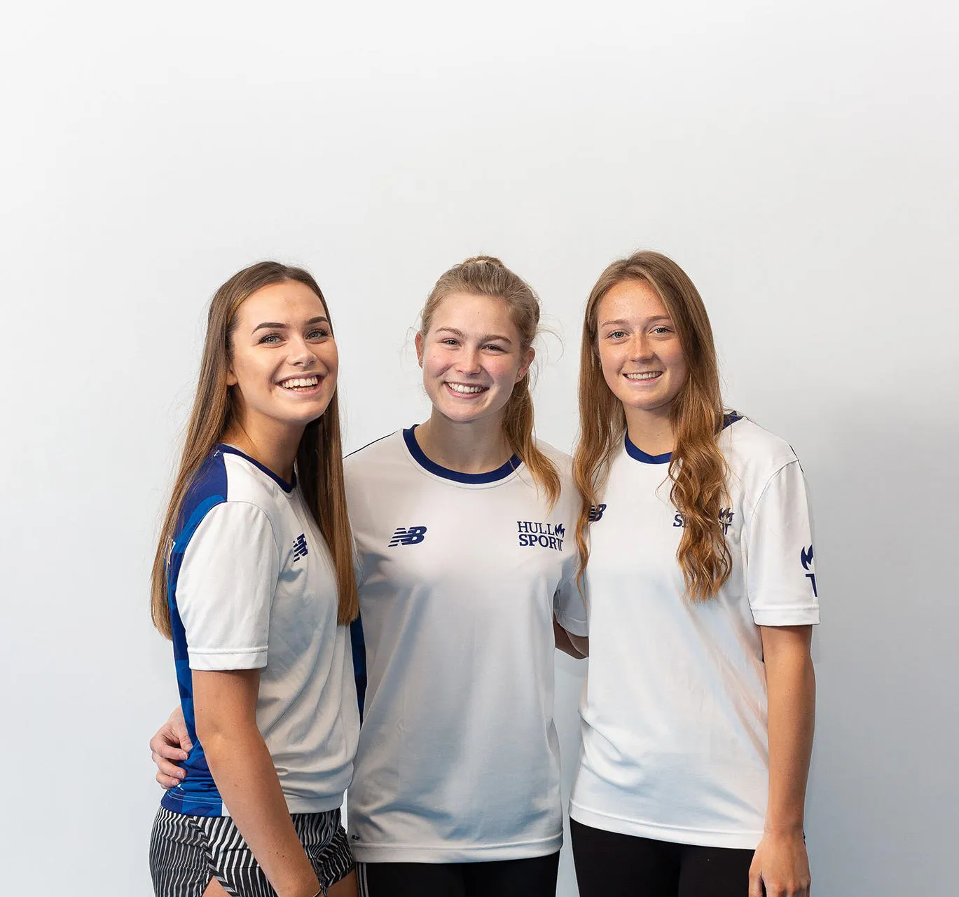 Three students hug in their sports uniform