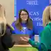A member of staff greets prospective students on a help stand at an Open Day