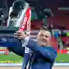 man in blue suit holding trophy aloft