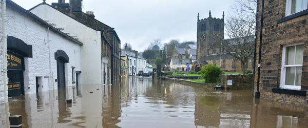 Flood waters lap against houses and businesses around a village green 