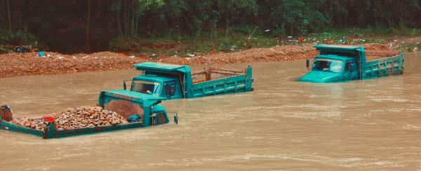 Partially submerged delivery trucks in a flooded river