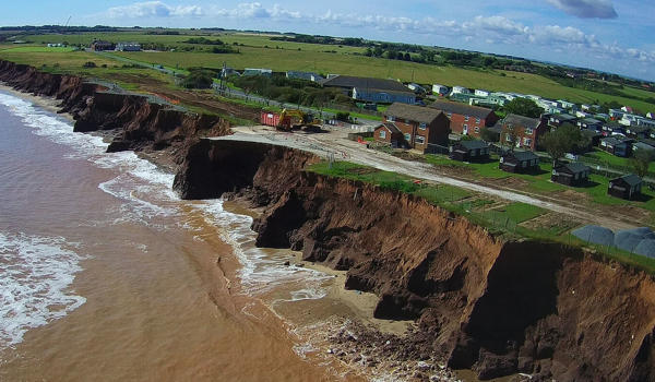 Aerial view of the Holderness coast showing the erosion of the soft earth cliffs and houses nearby