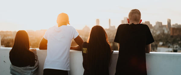 A group of young people look towards a sunset