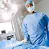 A female student wearing blue scrubs stands in an operating theatre 