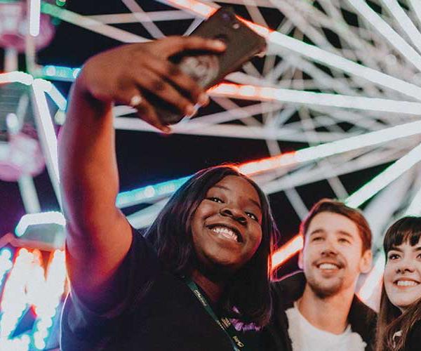 A group of three friends stop for a selfie in front of the big wheel at Hull Fair.