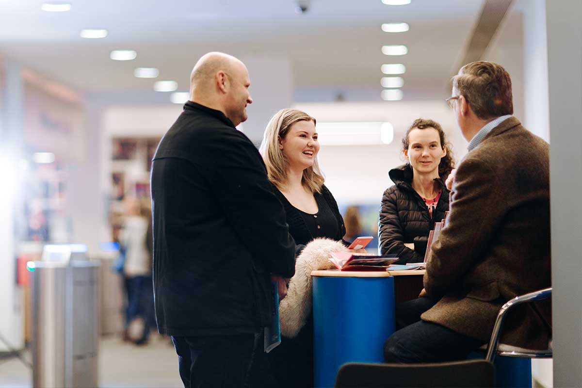 A girl and her parents talk to a member of staff at a stand at one of our Open Days