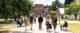 A group of students and parents walk down the central walkway on campus, below trees and colourful bunting