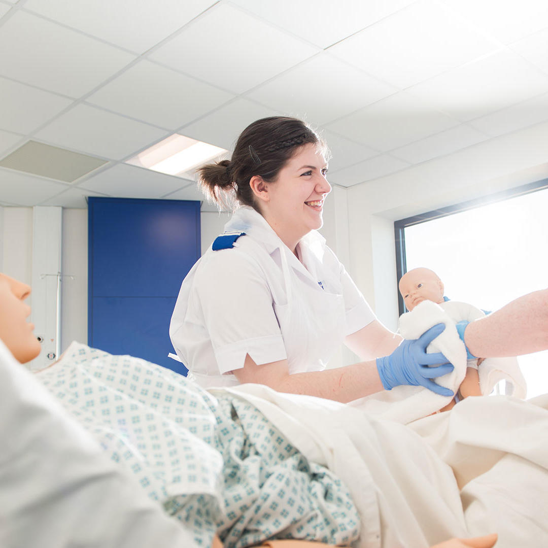A midwifery student practises on a dummy baby in a simulated neonatal ward