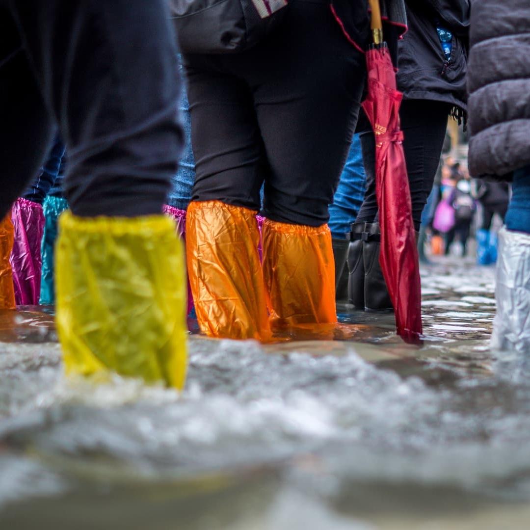 A group of people wading through flood water in protective footwear