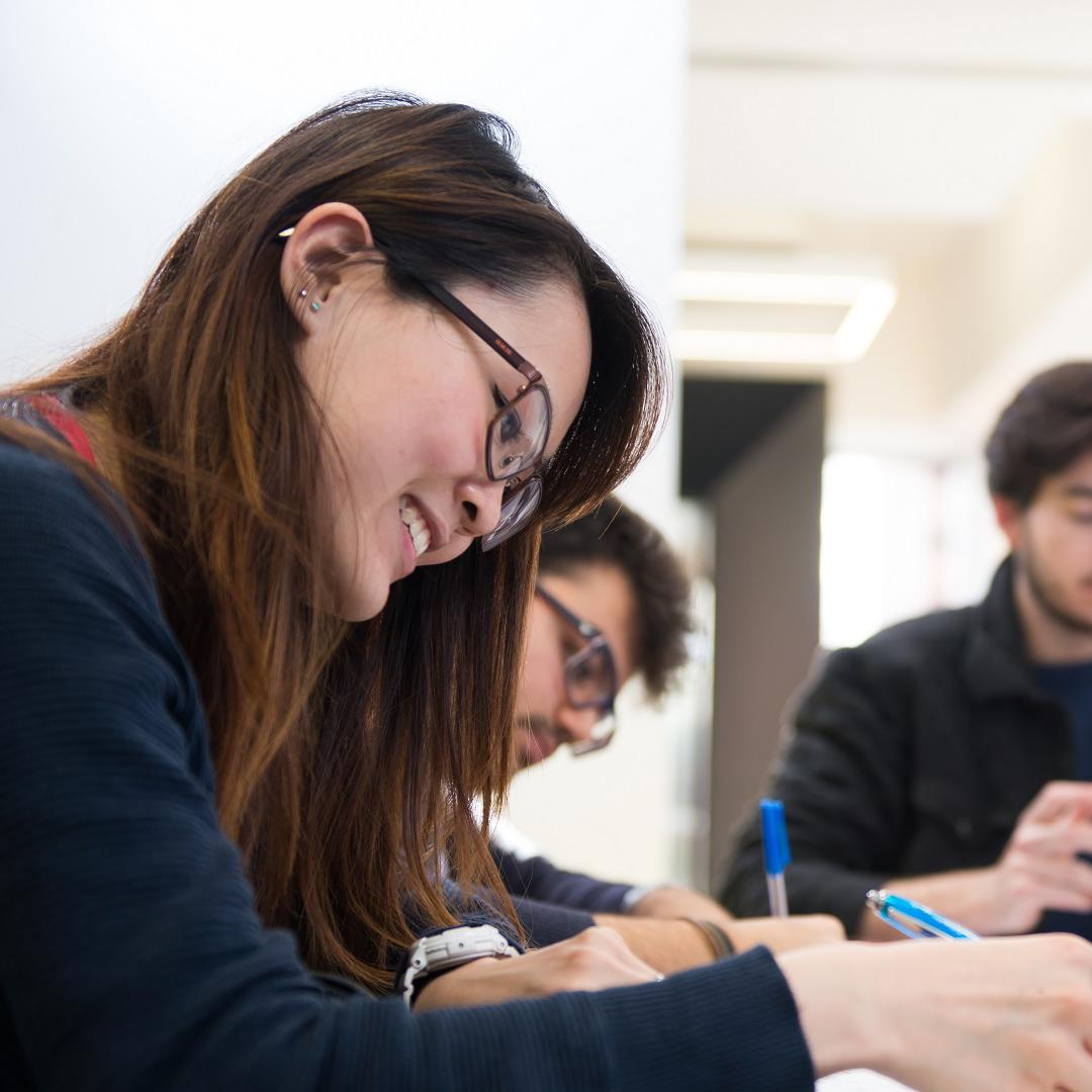 A group of students sitting with laptops and notepads in the library