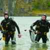 Two men wearing wetsuits walking out of the water