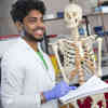 A biomedical science student in the lab holding a skeleton