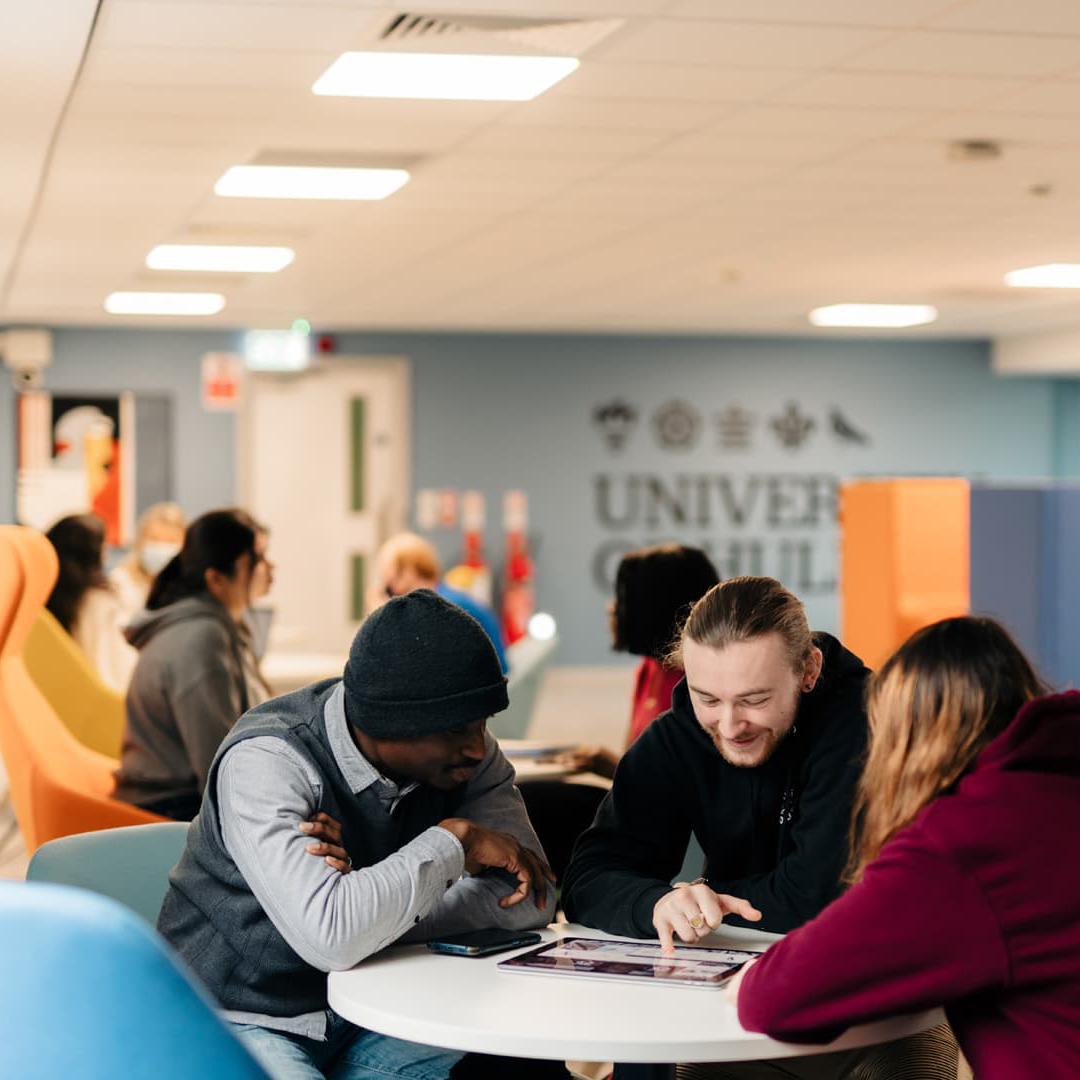 A group of students sit around a table in the Business Lounge