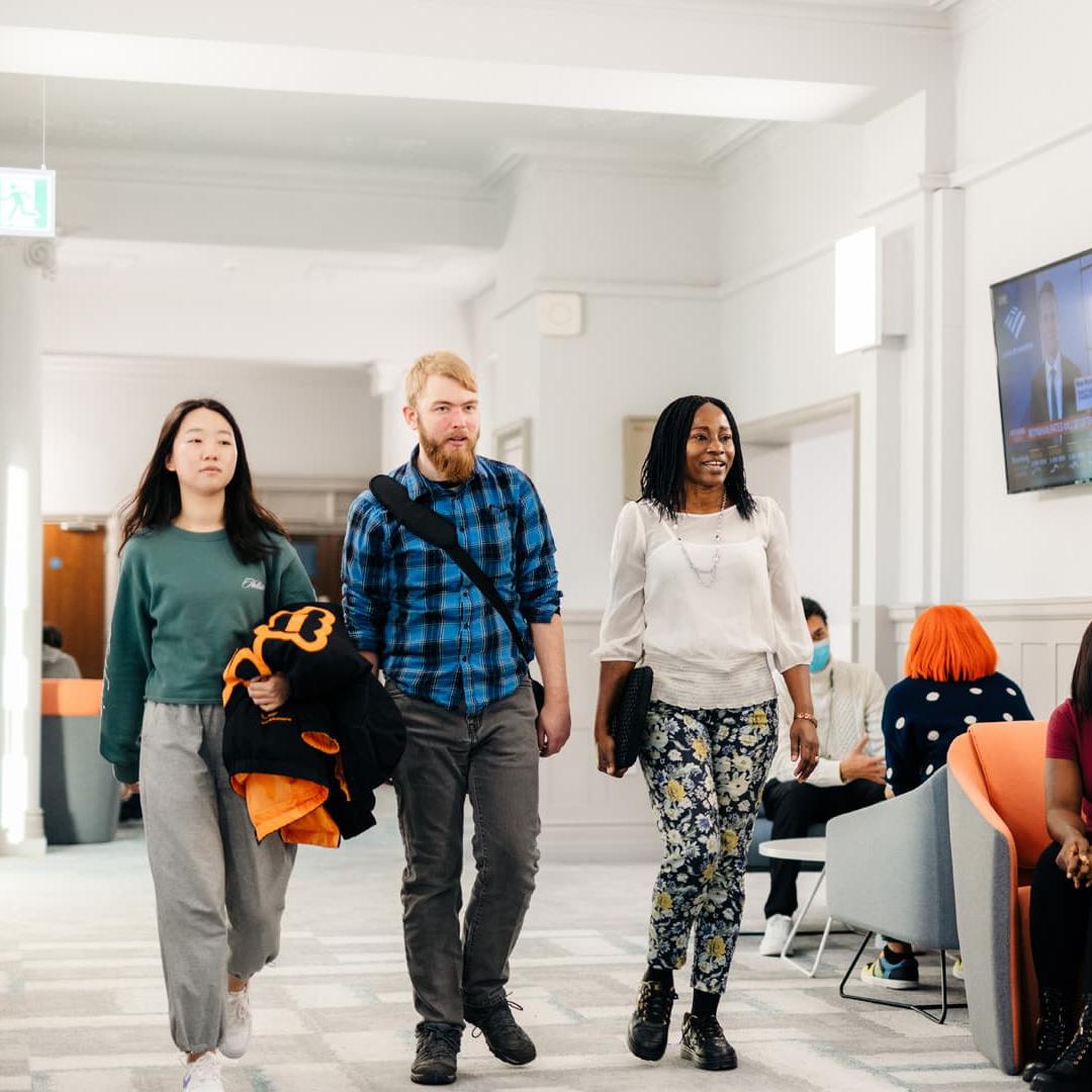 Three students walk through the Executive Education Suite in the Business School