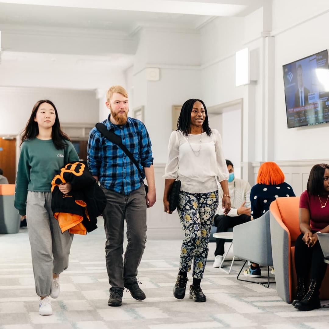 Three students walk through the Executive Education Suite