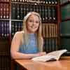 Hull History student, Hannah England, sits smiling with an open book in the Brynmor Jones Library, University of Hull.