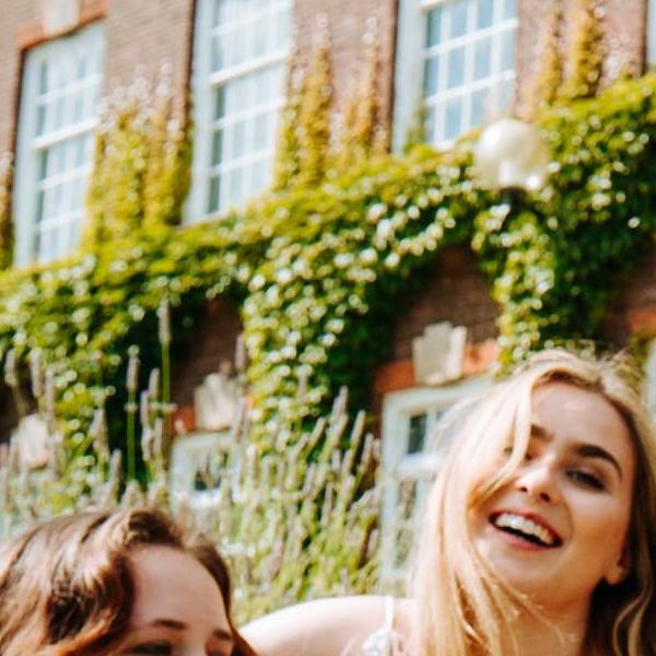 A group of students laugh outside a university building