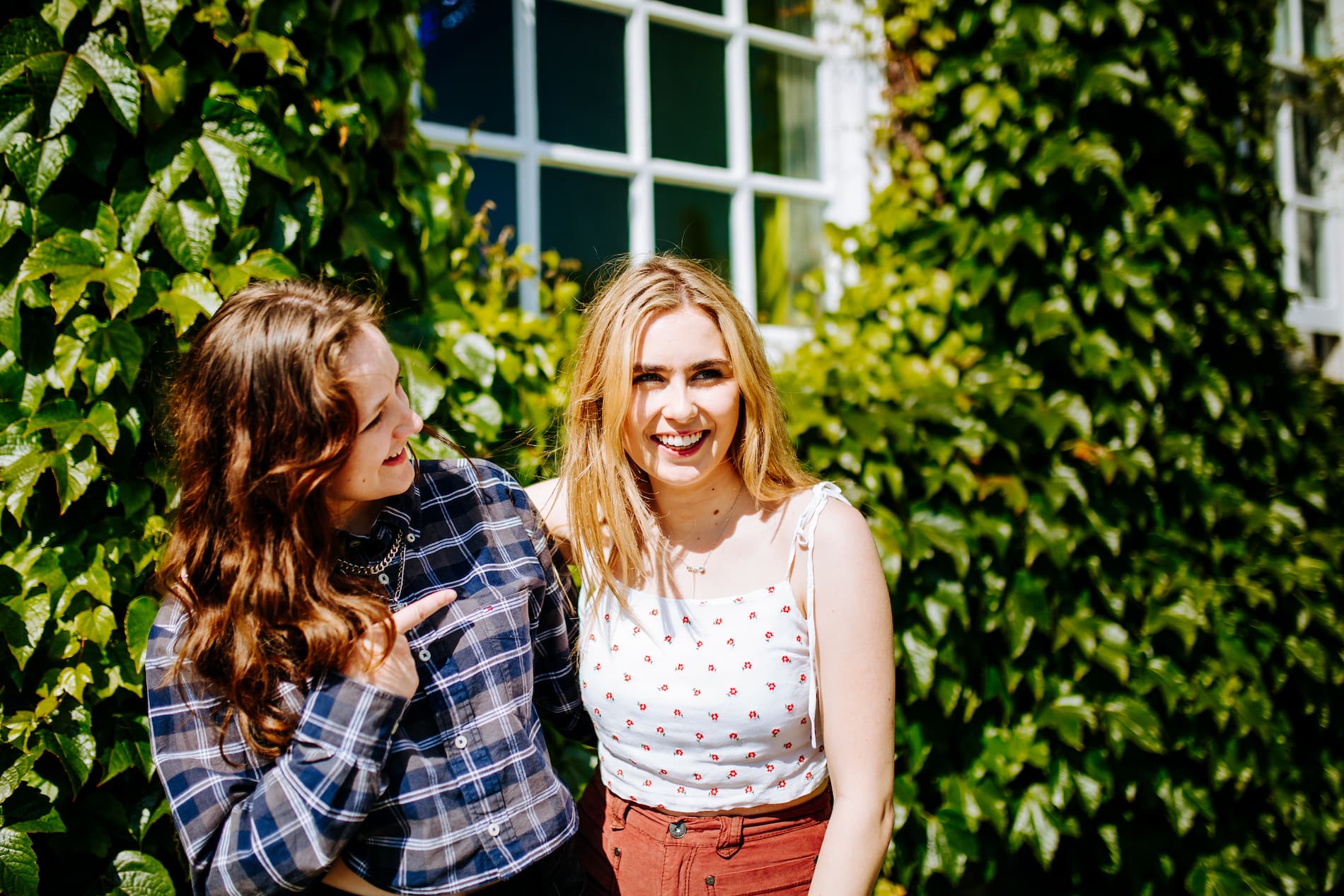 Two students pose in front of an ivy-clad university building