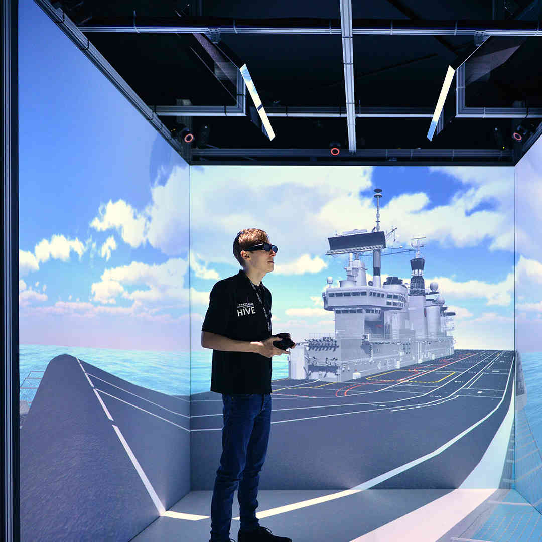 A student wearing a VR visor standing in the HIVE cube
