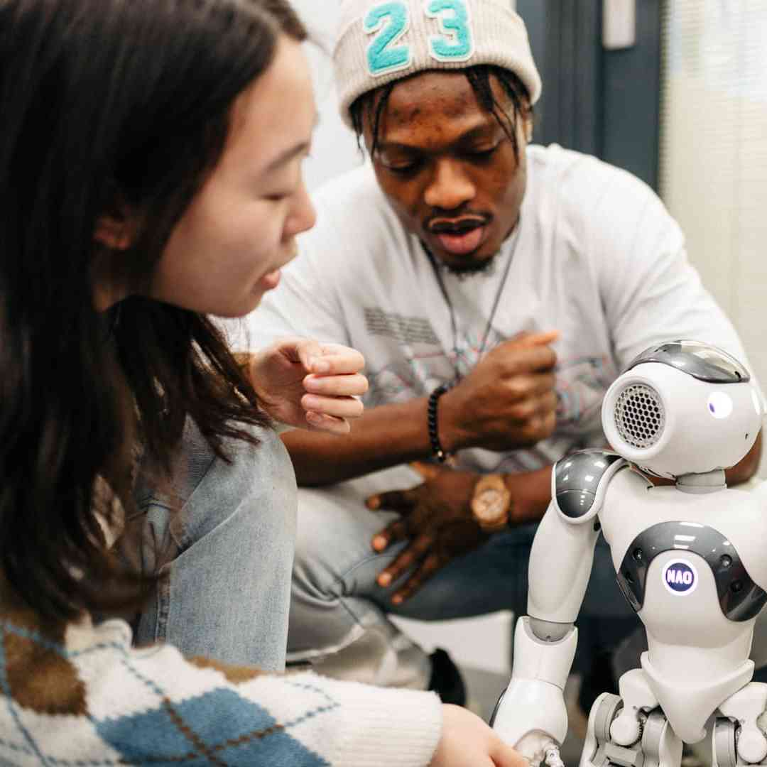 Students examine a small robot in the Robotics Lab