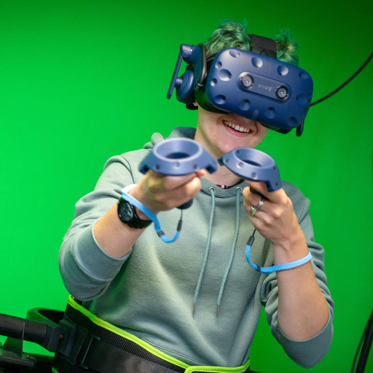 A student wearing a VR headset on a green screen