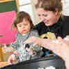 A teacher and small child play with craft materials in a classroom