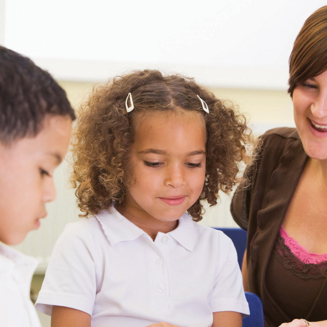 Schoolchildren and their teacher reading in classroom
