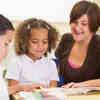 Schoolchildren and their teacher reading in classroom