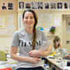 Hull Film Studies student, Lucy Meer, smiling and holding a notepad and pen while students write on laptops behind her.