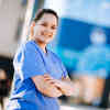 An ODP student in surgical scrubs standing outside the allam medical building