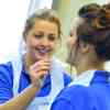 A nursing student wearing a protective gown takes an oral swab from another student