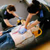 Two student paramedics practising on a dummy patient