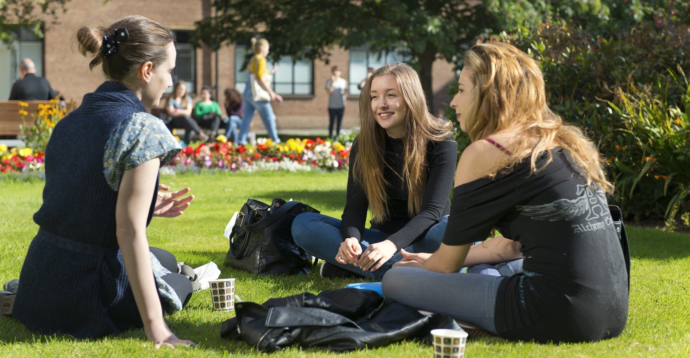 Female Students sat on Campus Lawn Landscape