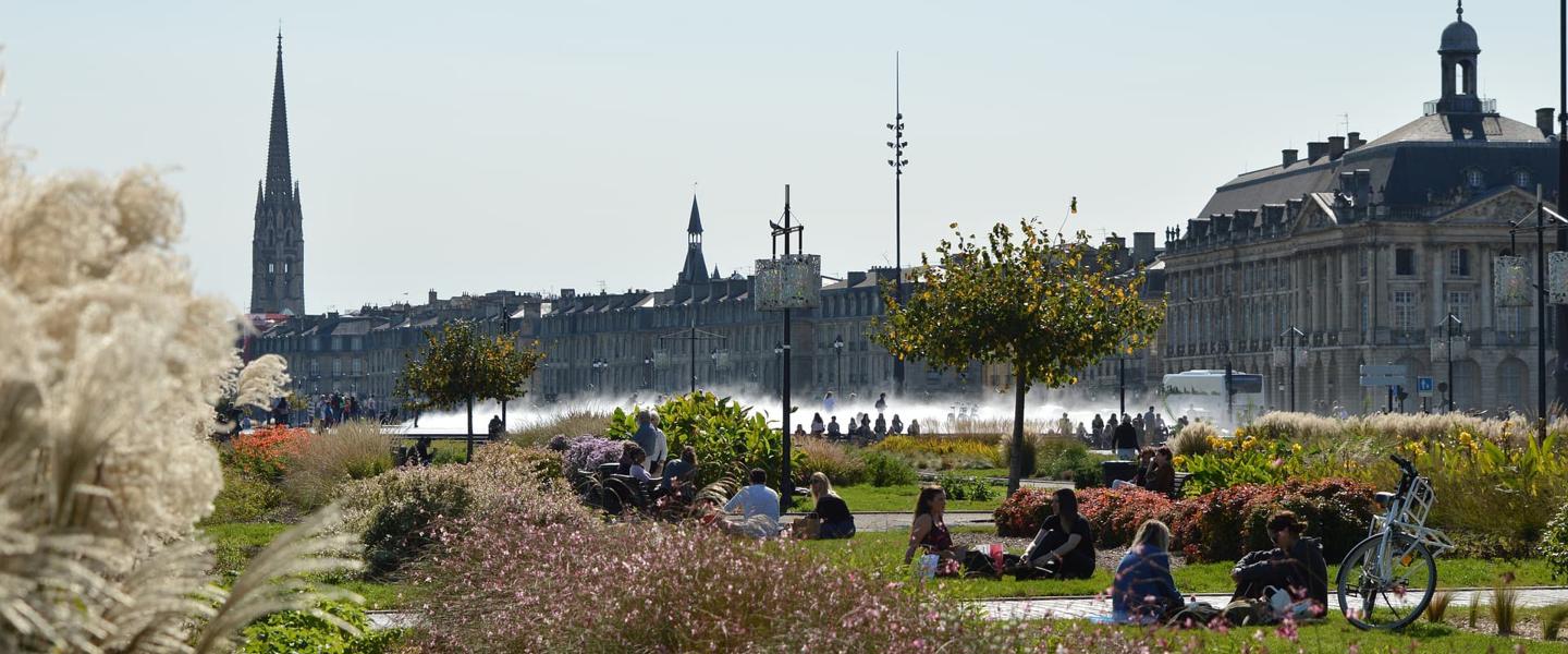 People relax on the grass in a park in Bordeaux on a sunny day