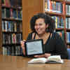 A female mathematics Student sat with an iPad in library