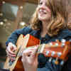 Hull Music student, Katrina Rae, smiling while playing a guitar.