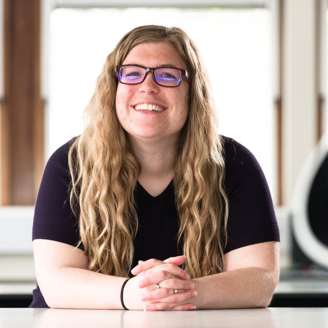 Astrophysics student poses in the laboratory next to a telescope